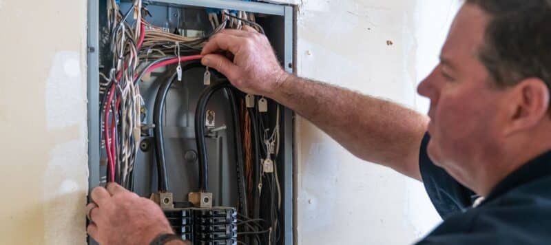 friendly mccullough electrician adjusting wires inside circuit breaker box